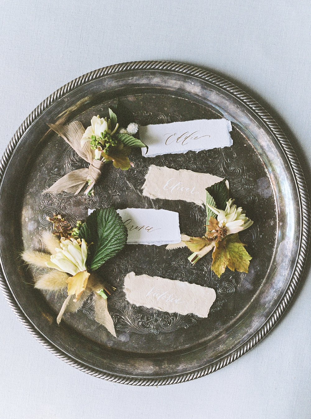 silver tray with spring boutonnieres, groom and groomsmen boutonnieres, calligraphy name tags, fine art film wedding photographer, spring wedding flowers, fall wedding flowers