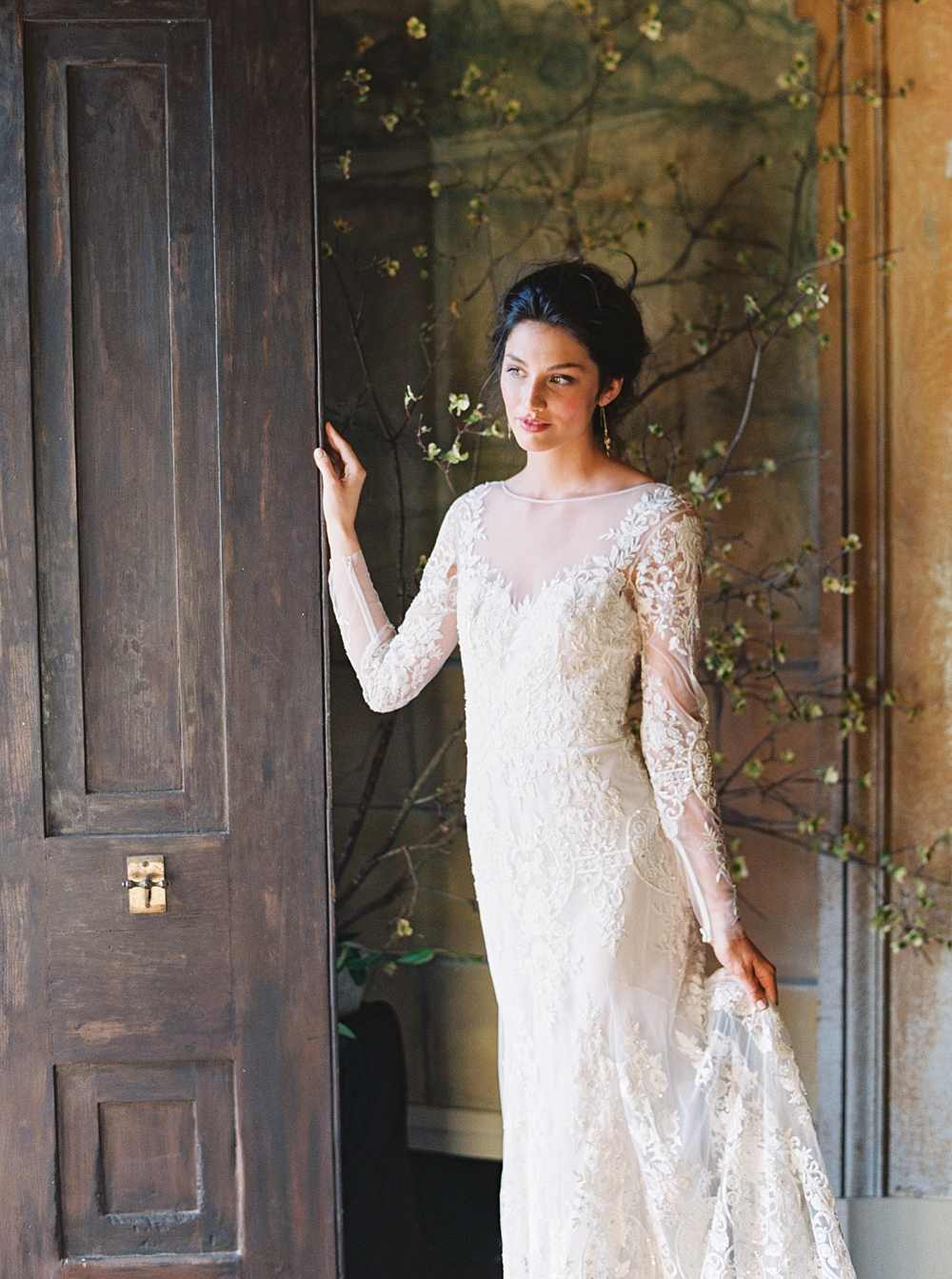 bride in doorway in front of flower wall historic mansion wedding, Charlottesville wedding, Riverwood mansion wedding, spring wedding, spring blossoms, long sleeve lace wedding dress
