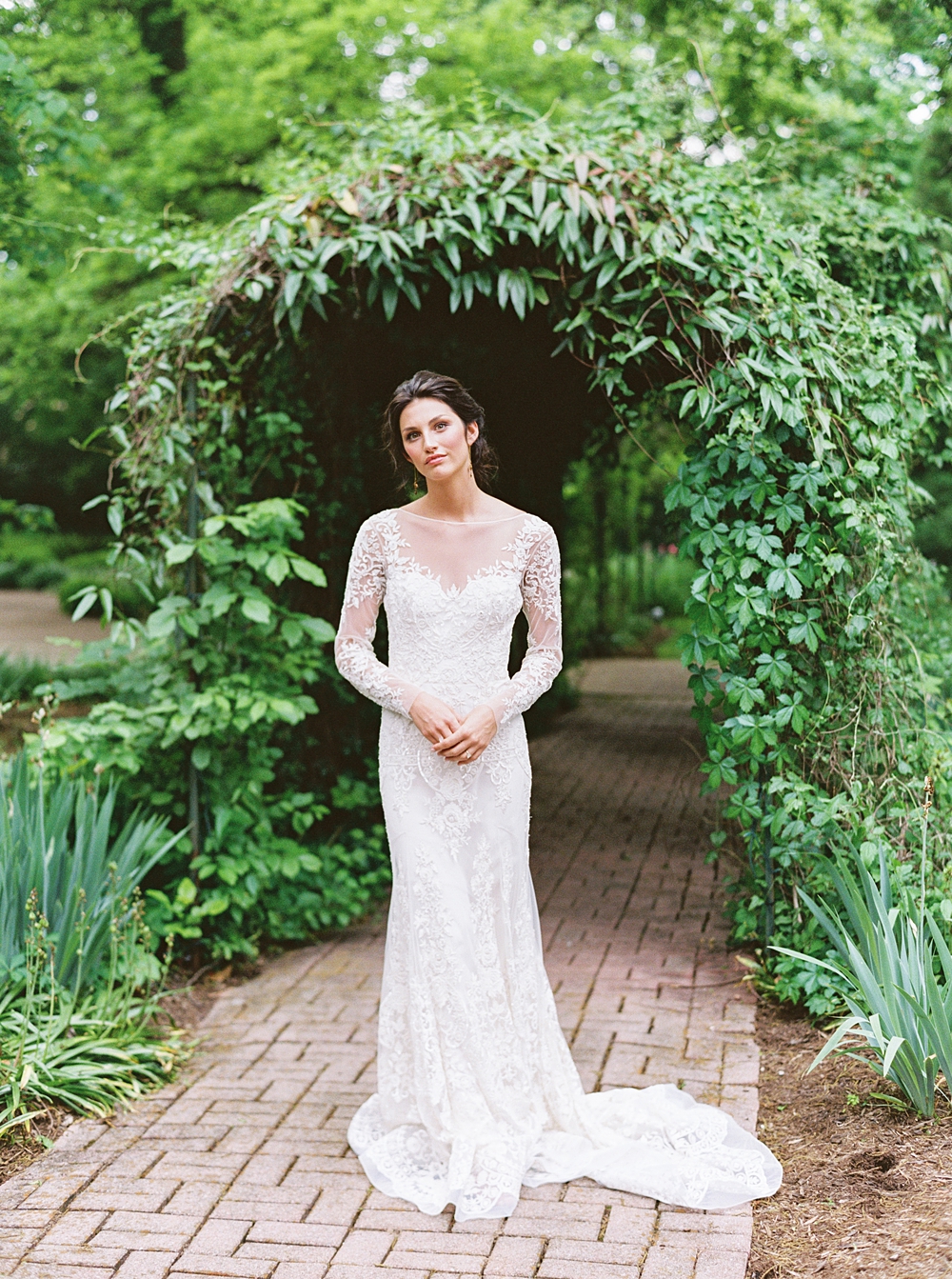 bride in long sleeve lace wedding dress in front of greenery arch, southern wedding photographer