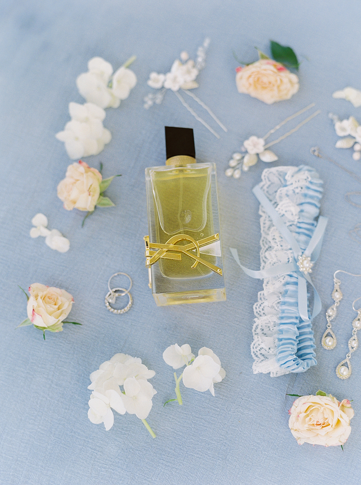 Wedding perfume and blue garter on light blue background, wedding photography flatlay details
