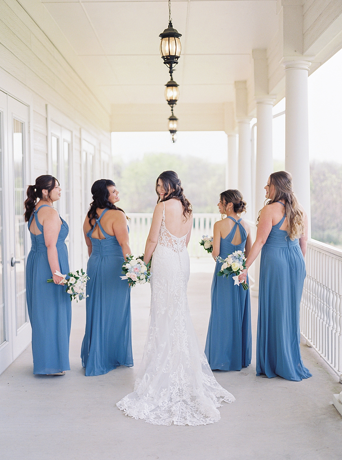 Bride in lace wedding dress with bridesmaids in dusty blue bridesmaid dresses, white bouquets