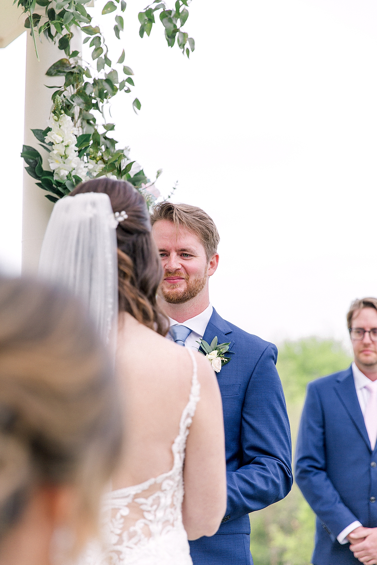 Groom in blue suit saying vows in outside wedding ceremony