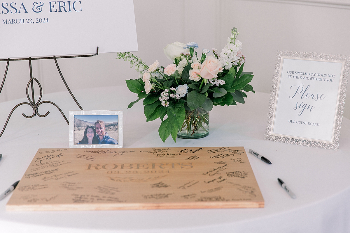 Wedding welcome table with guestbook and white and pink wedding flowers