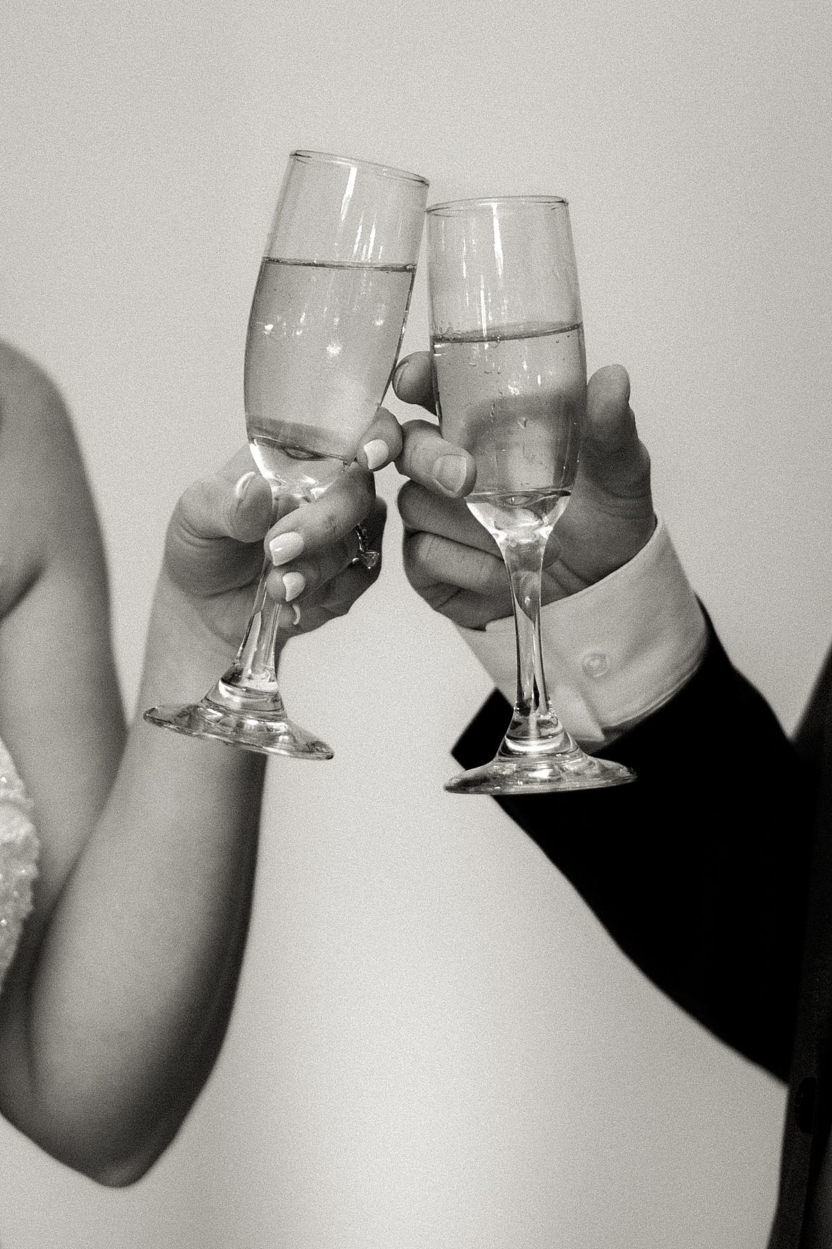 Bride and groom toasting champagne glasses for wedding toast, black and white fine art wedding photography