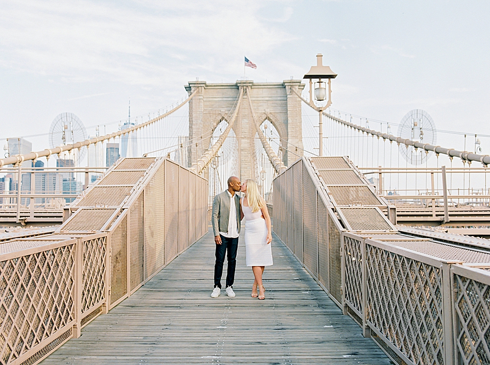 Engaged couple kissing on the Brooklyn Bridge